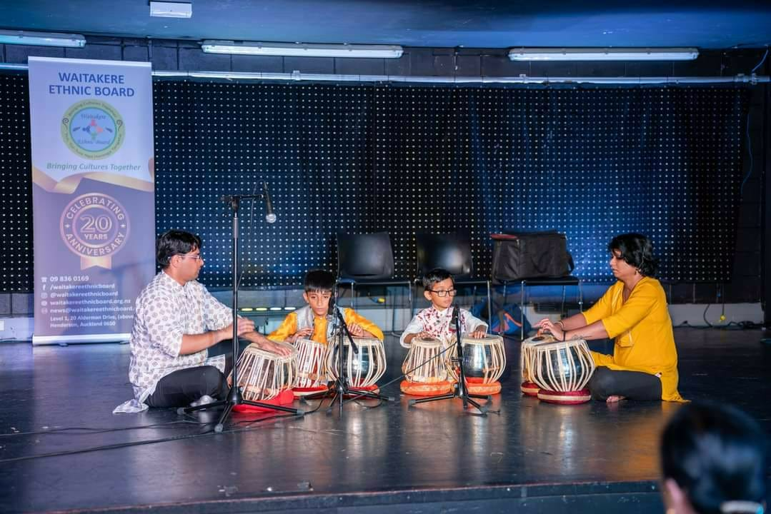 Teacher and young students performing tabla on stage at a Waitakere Ethnic Board event