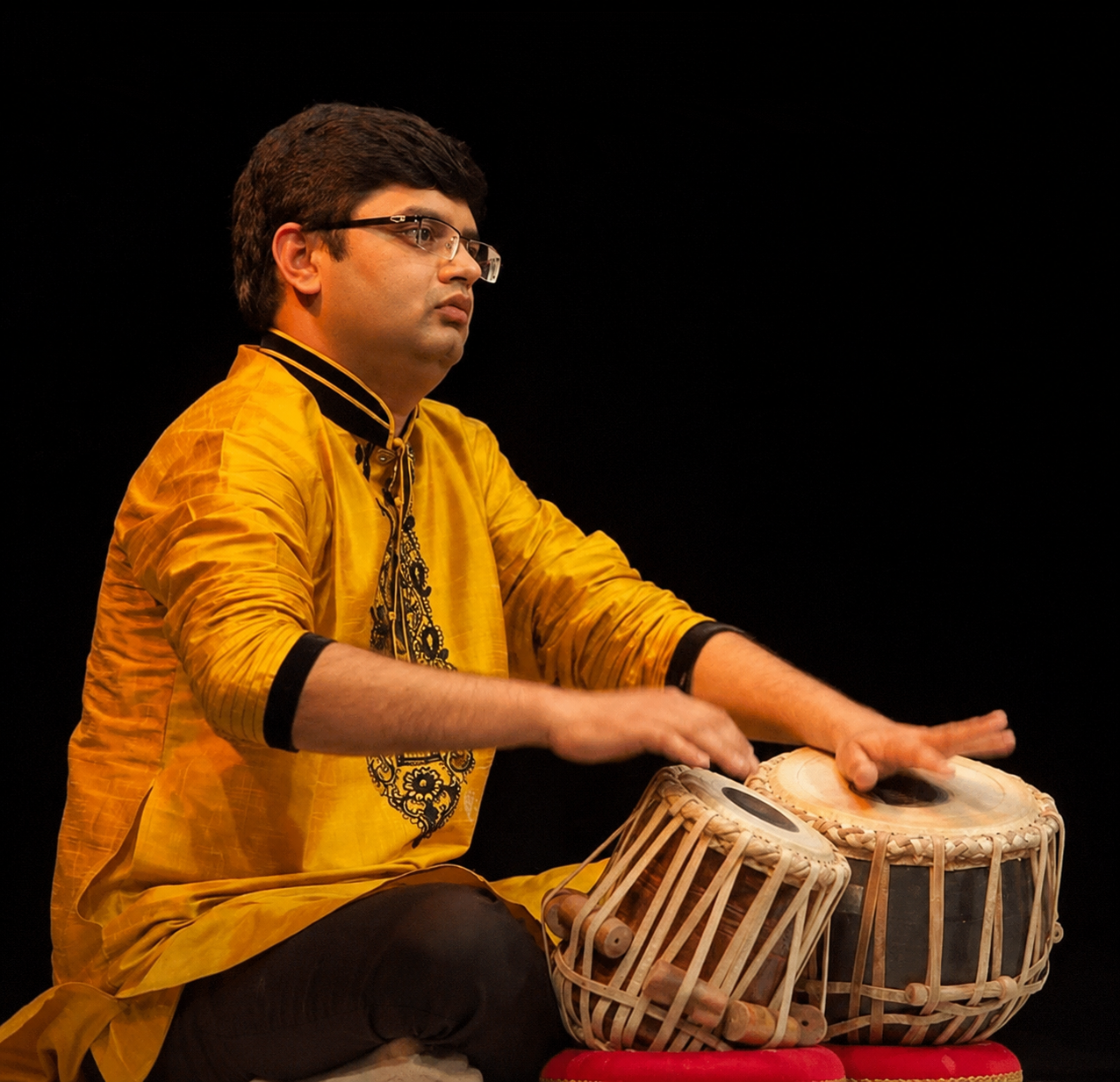 Arshav Raval performing on tabla in a yellow kurta