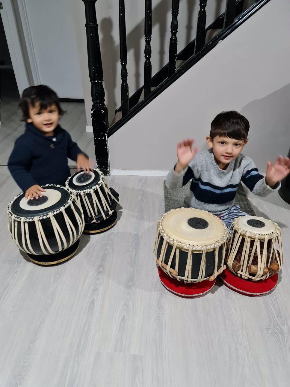 Two small children exploring tabla drums at home