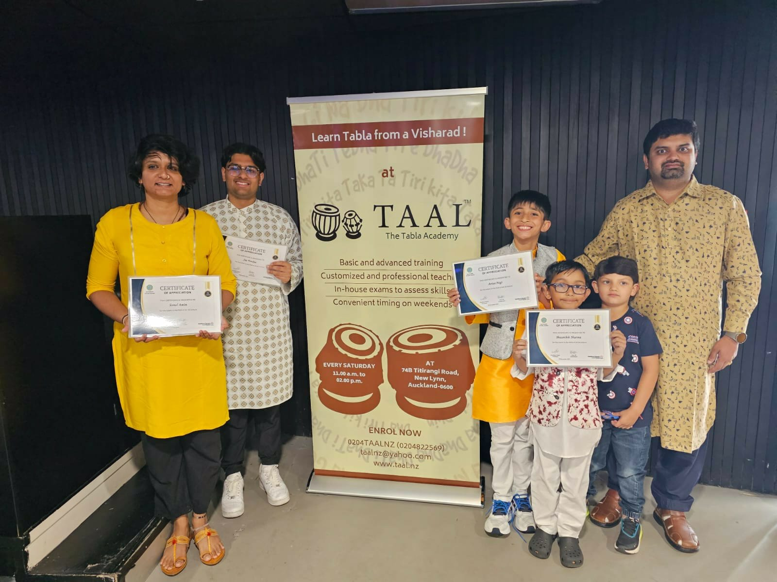 Students and parents with certificates beside the TAAL banner