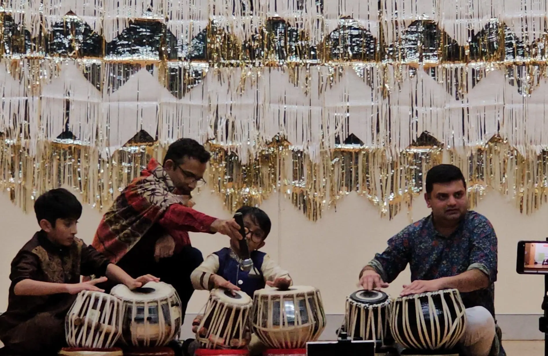 Students and teachers playing tabla together at a festival performance